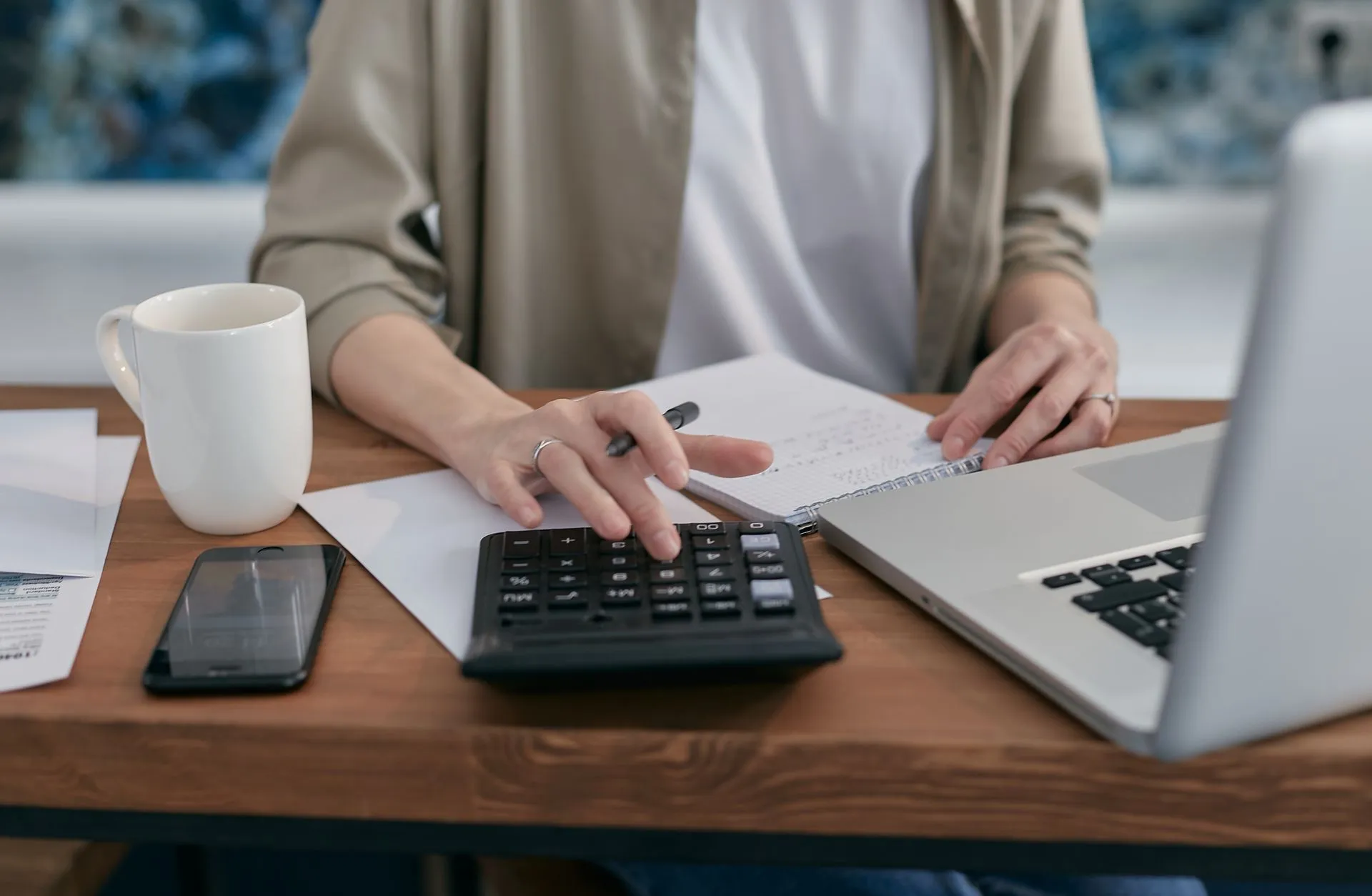 Manos usando una calculadora junto a una laptop